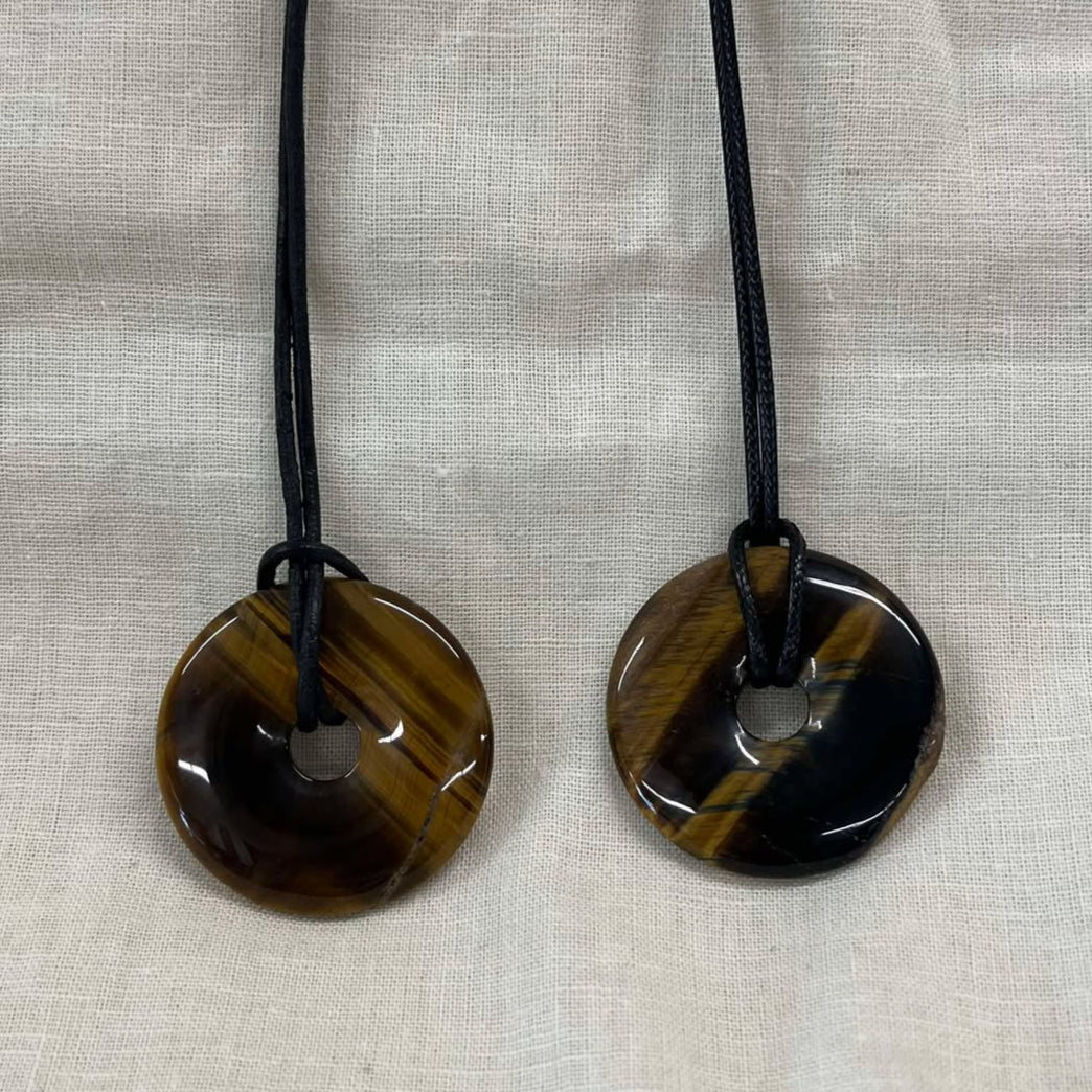 Two tiger eye circular stone necklaces on a beige fabric background