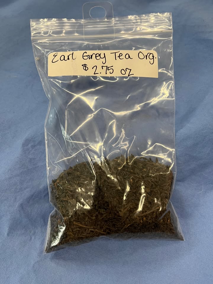 Dark brown dried tea leaves in a plastic zip bag, with label "Earl Grey Tea, Organic. $2.75 per oz."