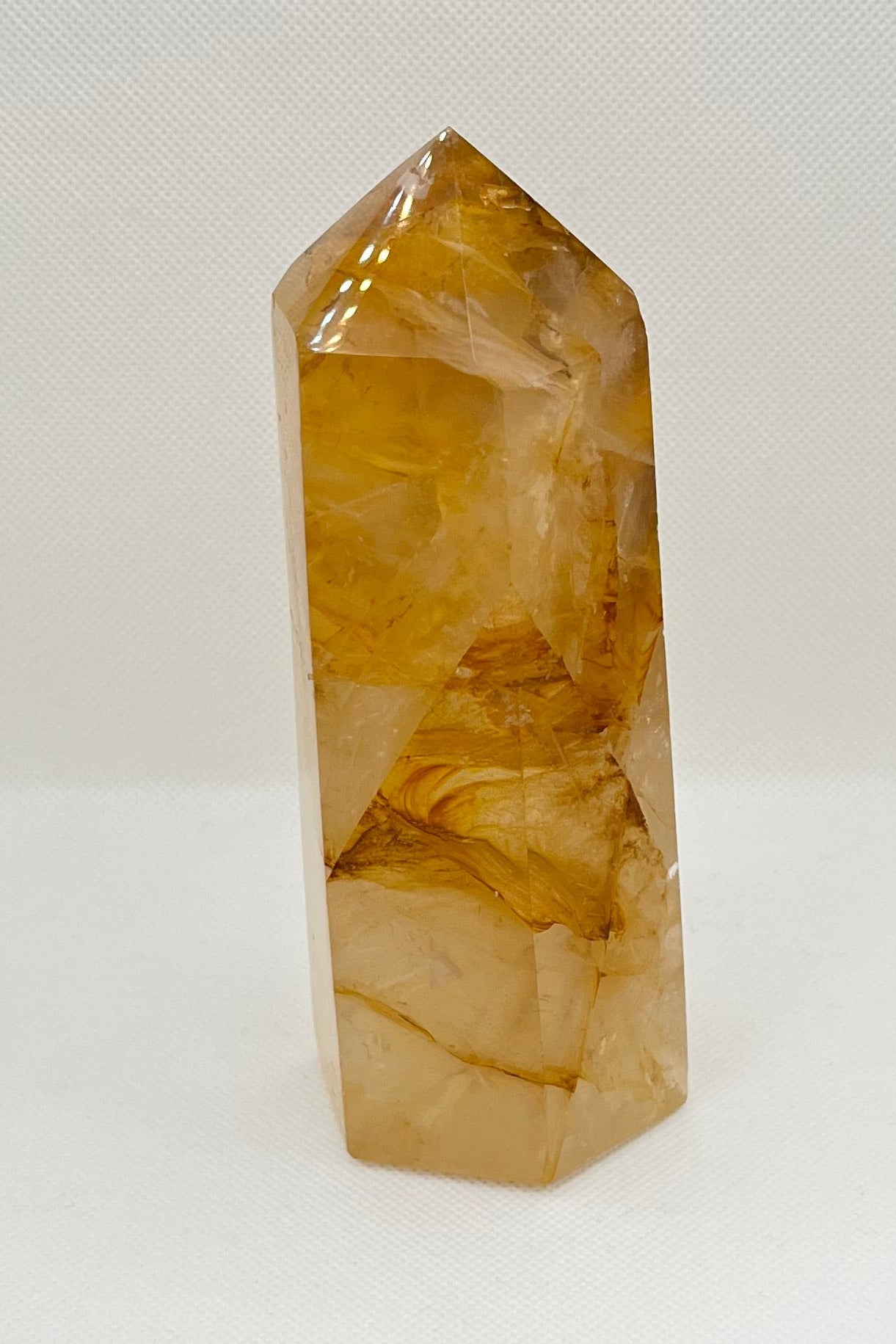 Clear quartz crystal with yellow and orange marbling on a white background