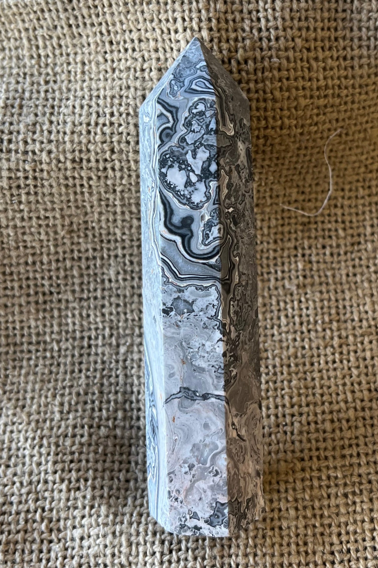 Decorative stone tower with mottled grey and white pattern on a textured fabric background