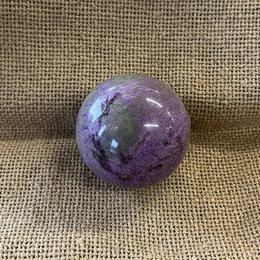 Purple marbled crystal ball on a textured beige surface