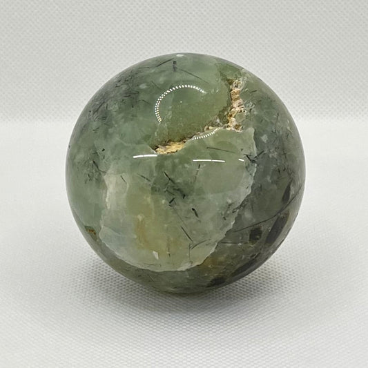 Green stone sphere on a white surface with a blurred background