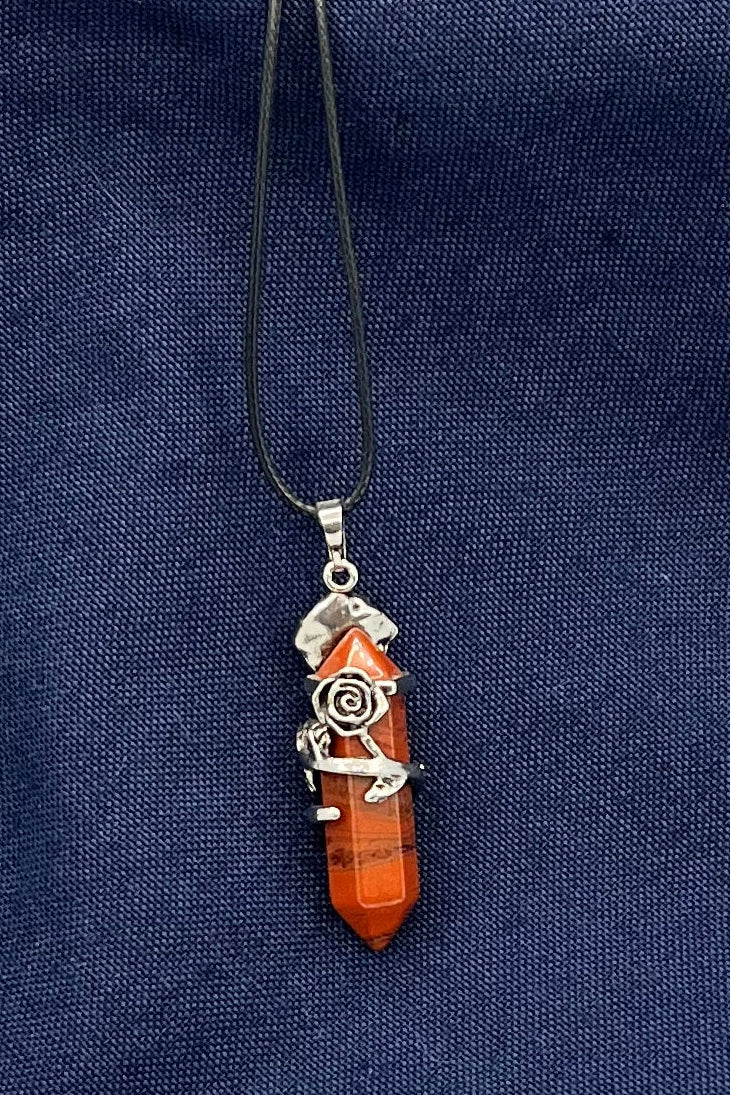 Double-pointed red jasper crystal affixed to a metal finding with a metal rose with stem and leaves wrapped around it.