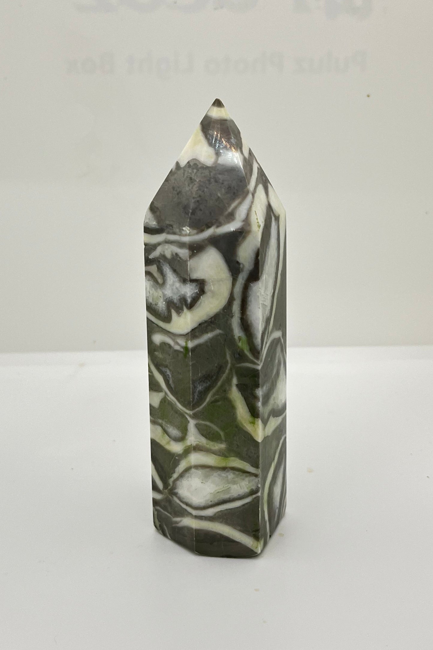 Marbled gray, white, and dark gray patterned crystal tower on a white background