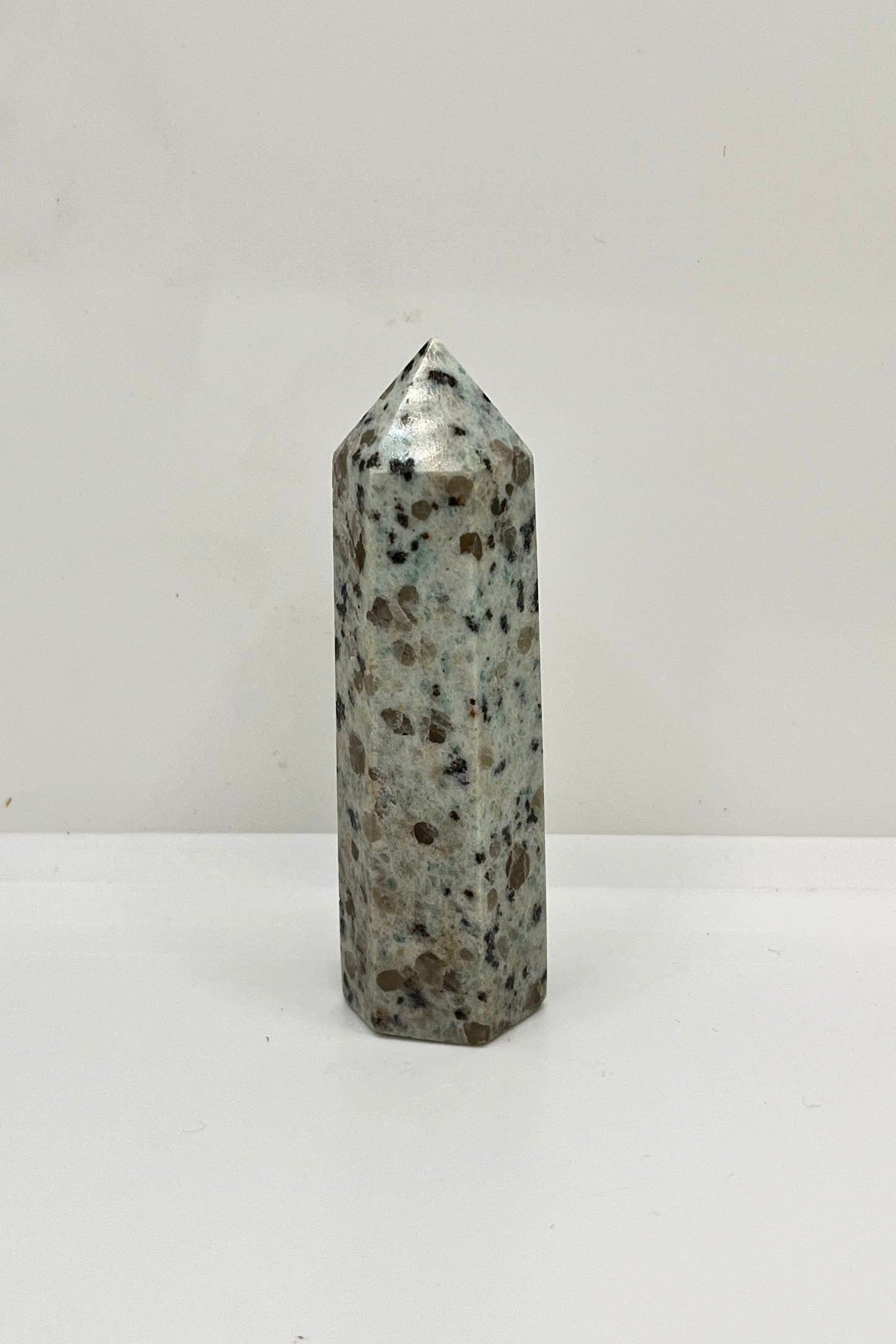 Gray speckled kiwi jasper stone tower on a white background