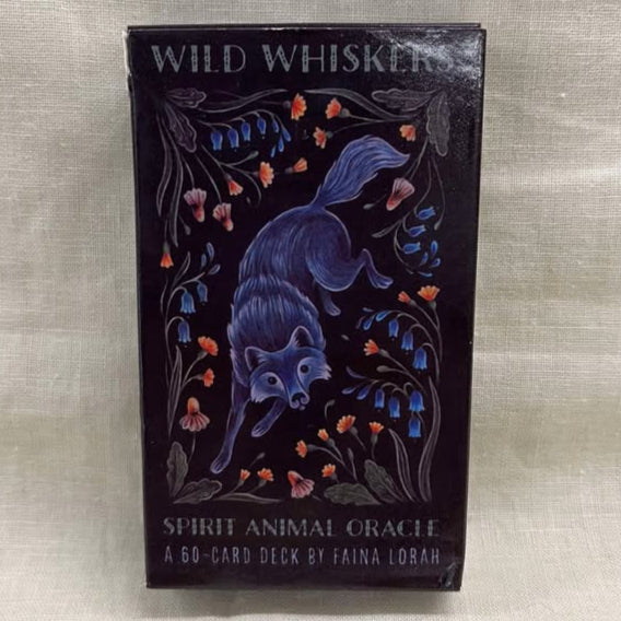 Ornate packaging of 'Wild Whiskers Spirit Animal Oracle' featuring a fox surrounded by flowers on a textured beige background