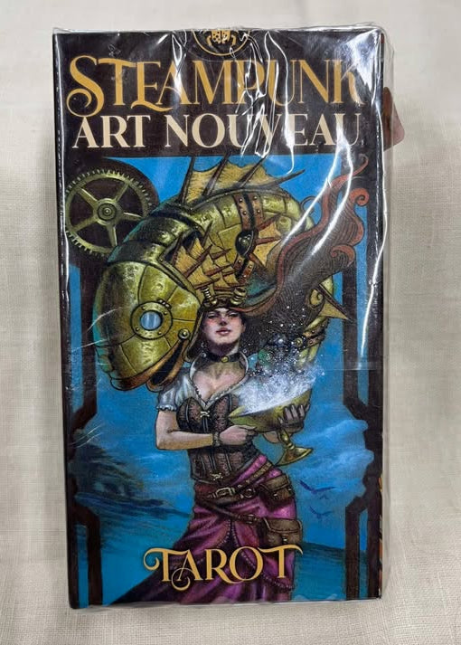 Steampunk Art Nouveau Tarot card deck front view - a woman in a shirt and skirt stands with a mechanical fish leaping over her, in front of a blue background with a gear.