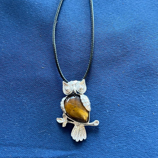 Necklace with metal owl pendant and tiger eye stone on a blue background