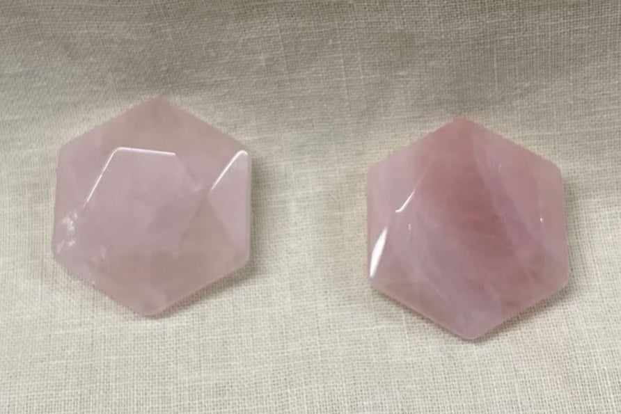 Hexagonal pink semi-transluscent rose quartz gemstones on a light fabric background