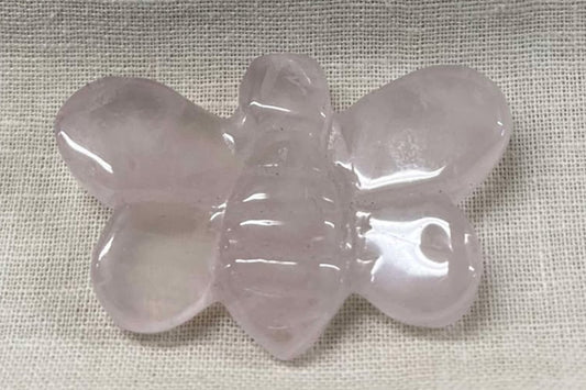Light pink crystal bumblebee with wings stretched out on a textured fabric background