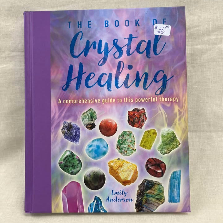 The book of crystal healing - a comprehensive guide to this powerful therapy. Book has a purple binding, with various colors and shapes of crystals on a multicolor background of purples, pinks, yellows, greens. 