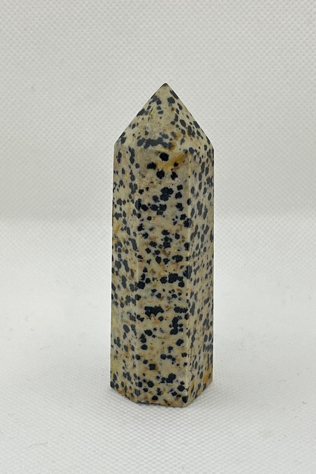 Tan crystal tower with 6 sides, with black and brown specs throughout the stone.  