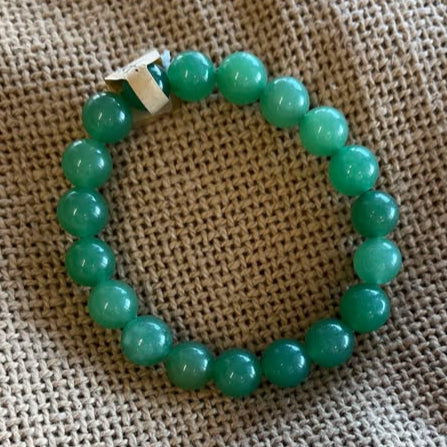 Green beaded bracelet on a textured beige fabric background