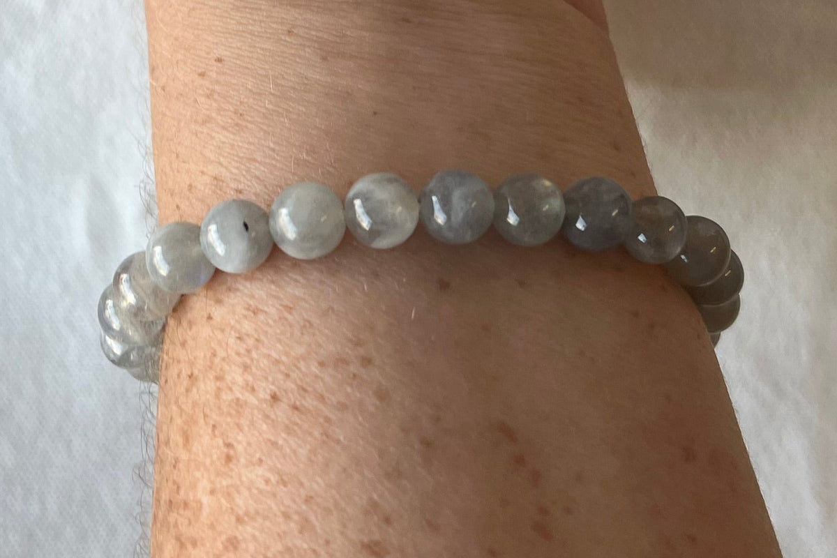 A bracelet of small gray semi-irridescent beads being worn by a freckled woman who should probably apply a lotion.