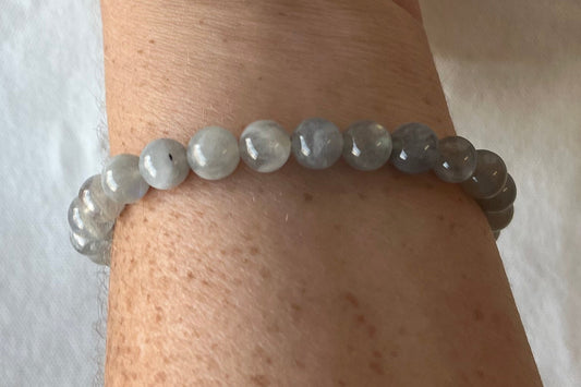 A bracelet of small gray semi-irridescent beads being worn by a freckled woman who should probably apply a lotion.
