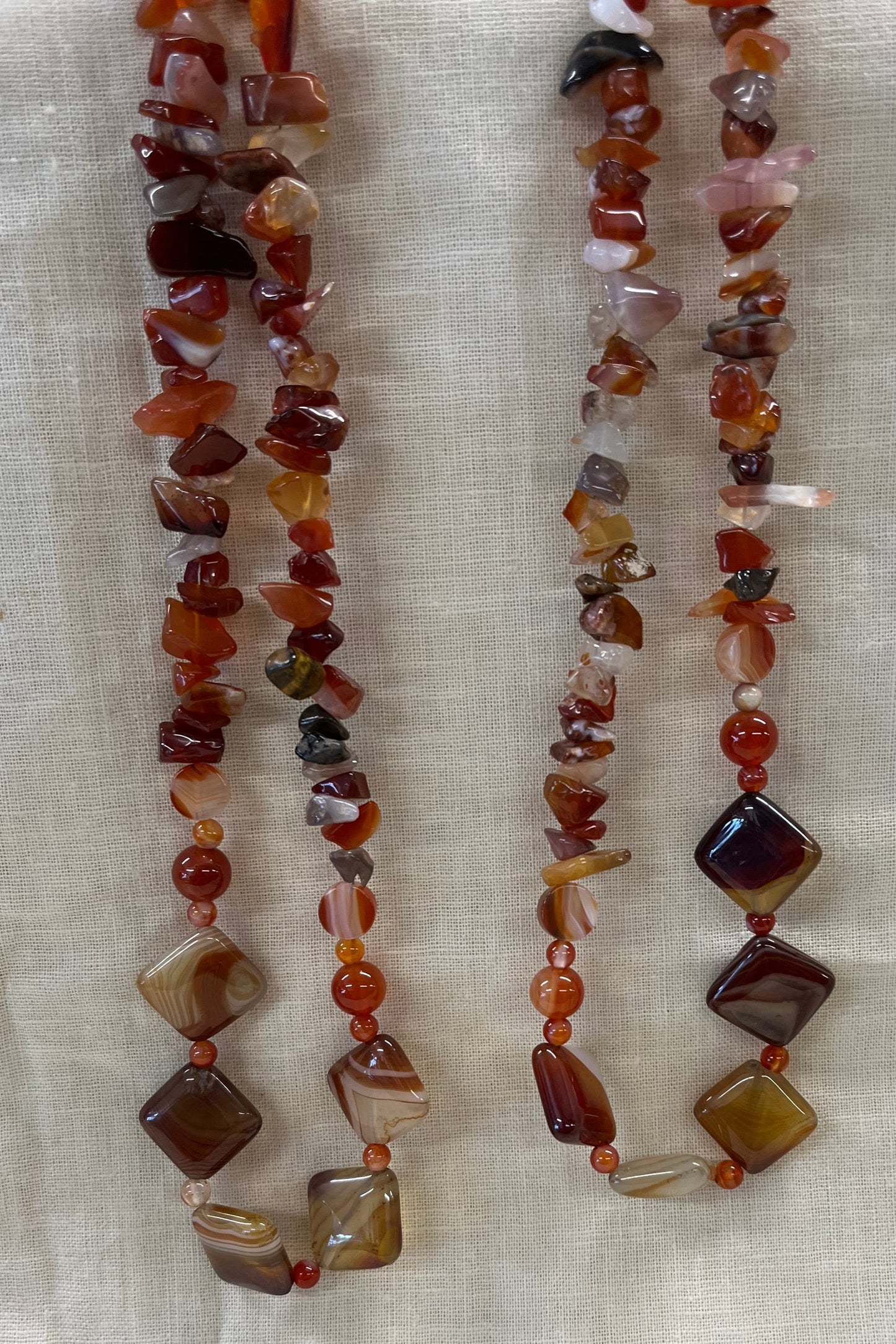 Two beaded necklaces on a light fabric background