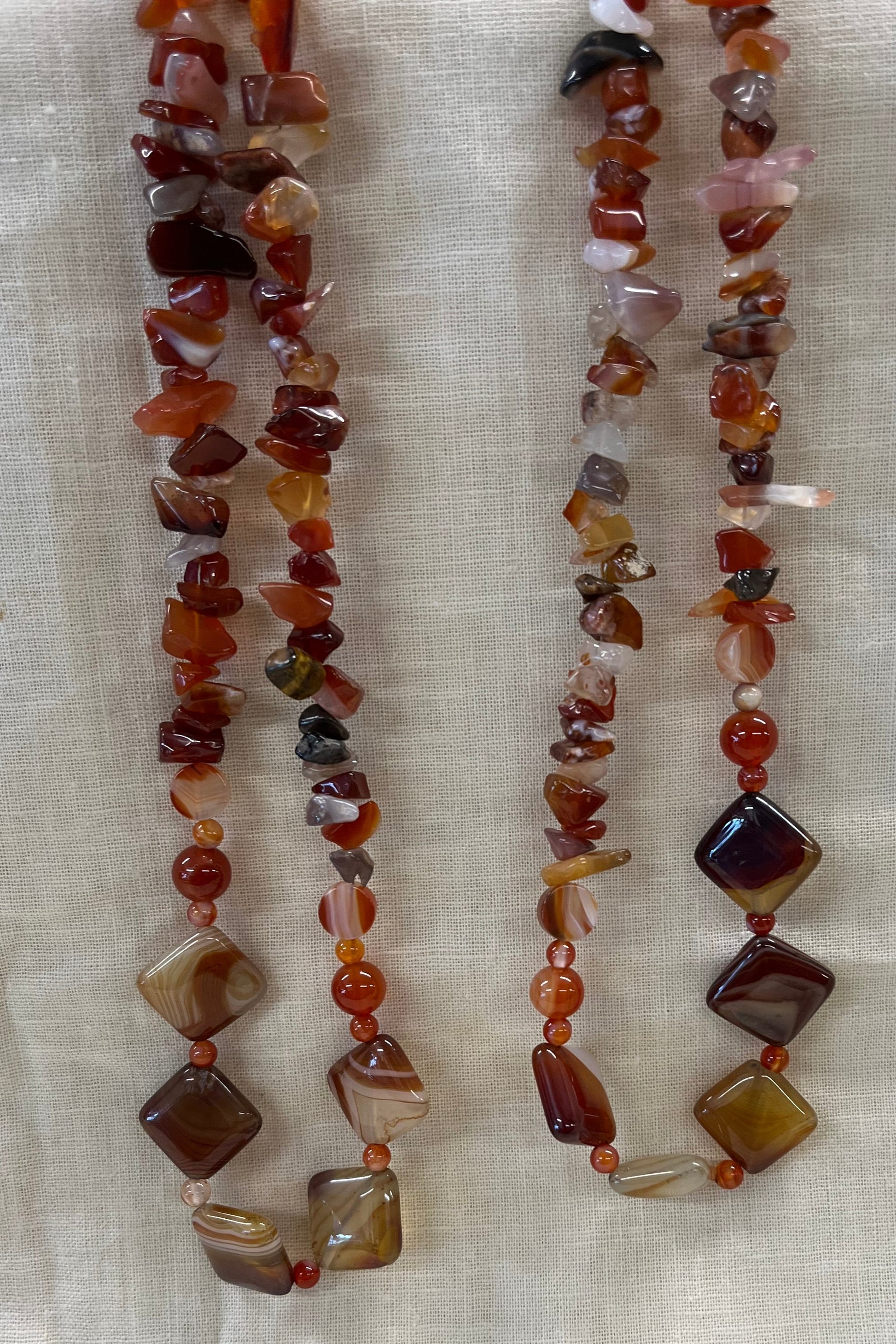 Two beaded necklaces on a light fabric background