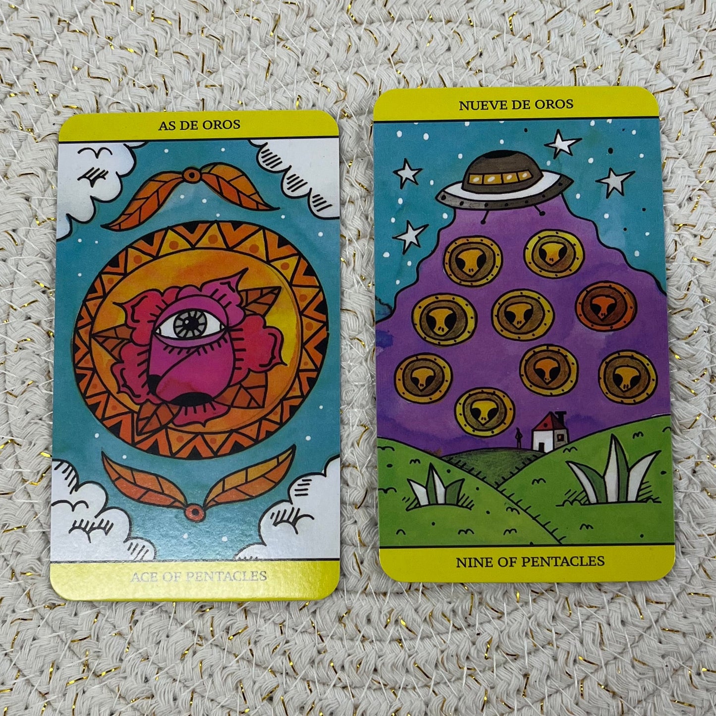 Two tarot cards, one featuring a mandala with strange artistic designs difficult to describe, and one showing aliens being beamed to or from a spaceship hovering above a farm at night.