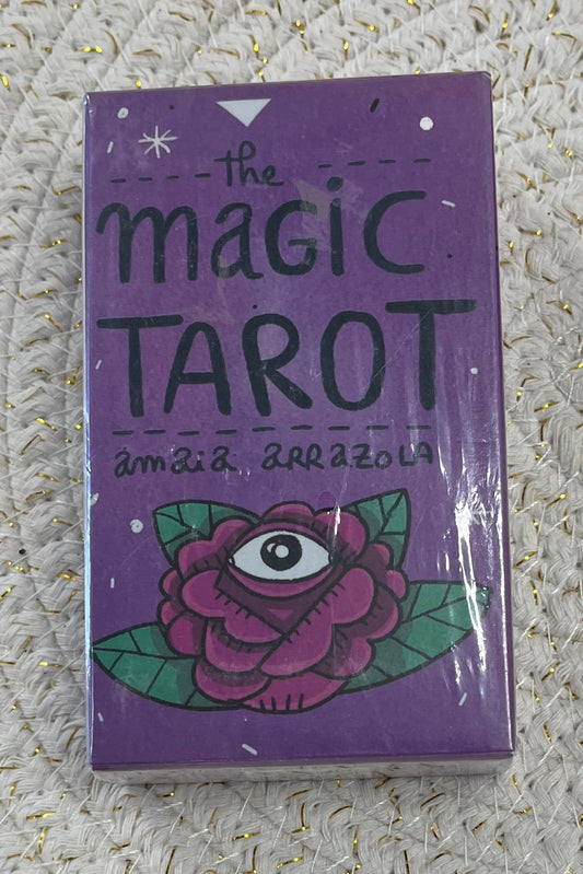 Purple tarot card box with handwritten words "the magic tarot" and "Amaia Arrazola" above a rose design with an eye in the middle.