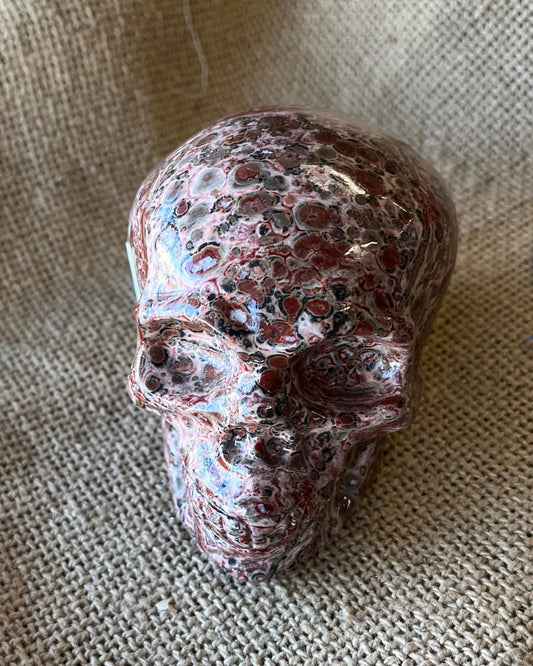 Brown mottled stone skull on a textured beige fabric surface