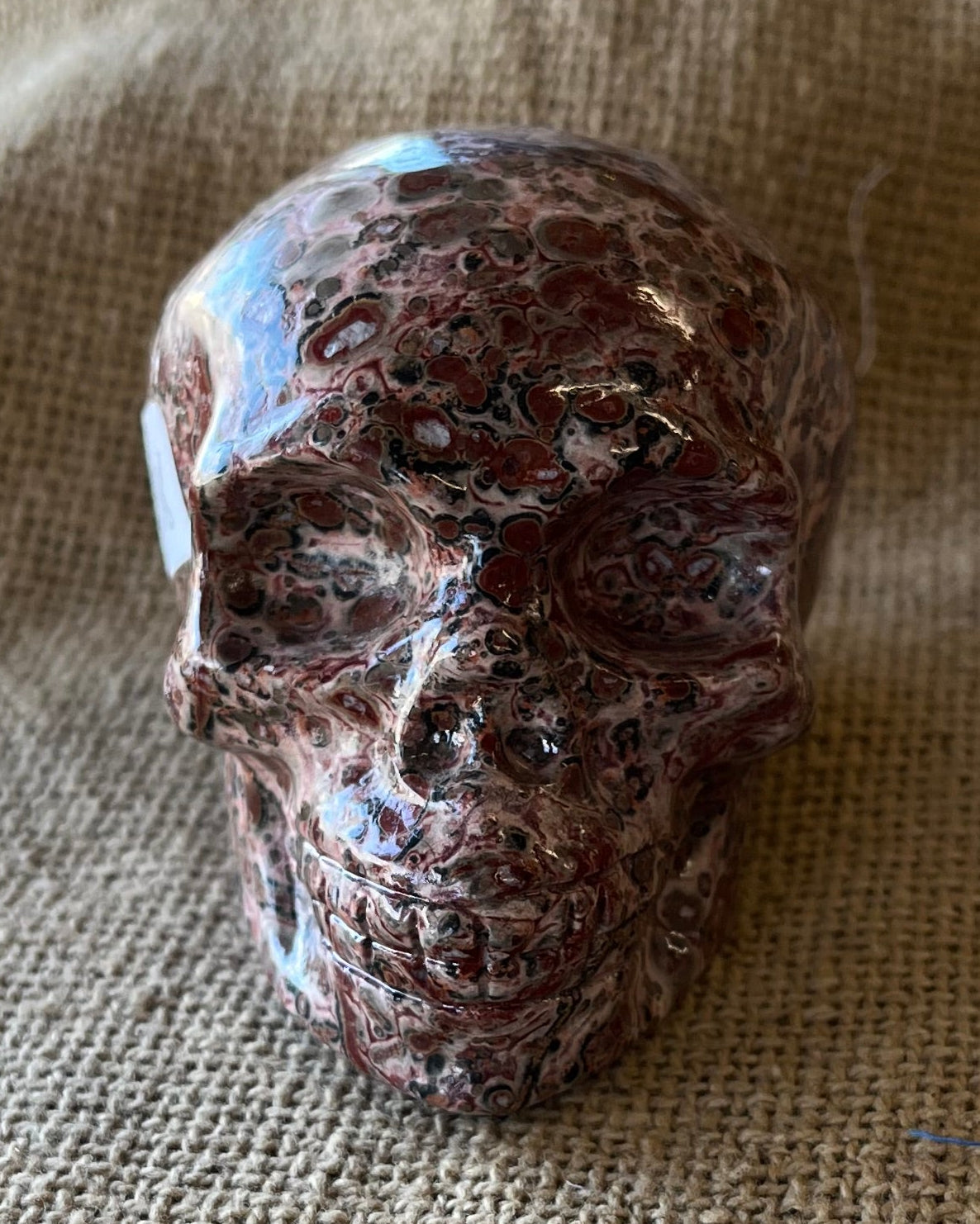 Brown mottled stone skull on a textured beige fabric surface