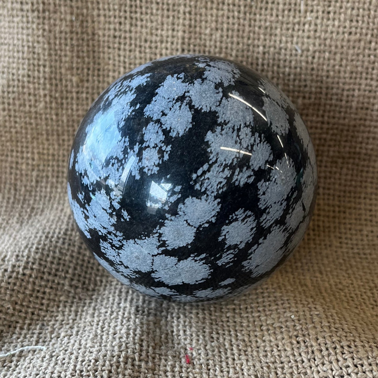 Black sphere with white snowflake pattern on a textured fabric background