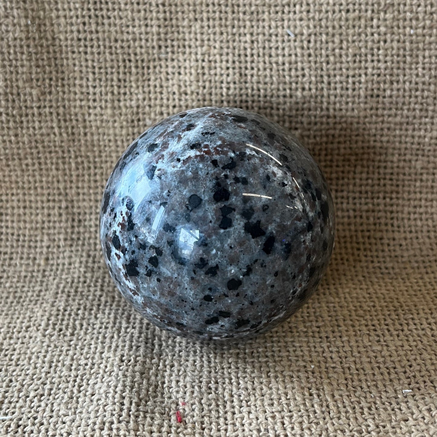 Gray black and tan crystal sphere on a tan textured background.