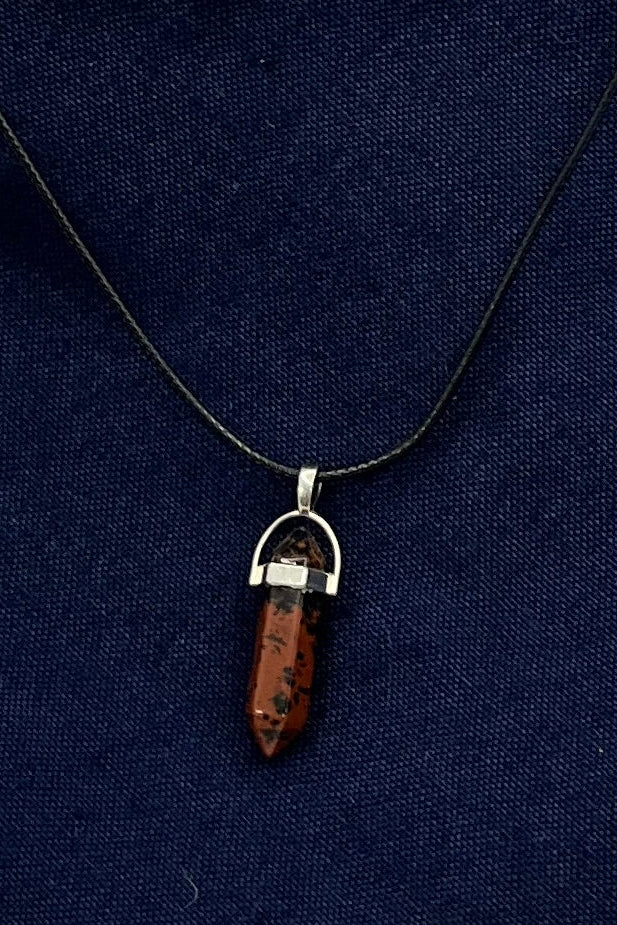 A black and red marbled double-pointed crystal in a metal finding on a black cord.