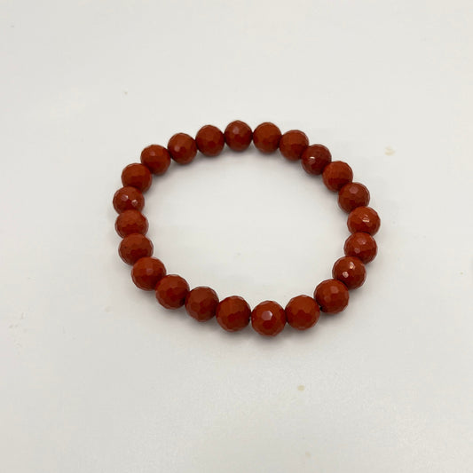 Rust colored beaded bracelet on a white background.  The beads are faceted.