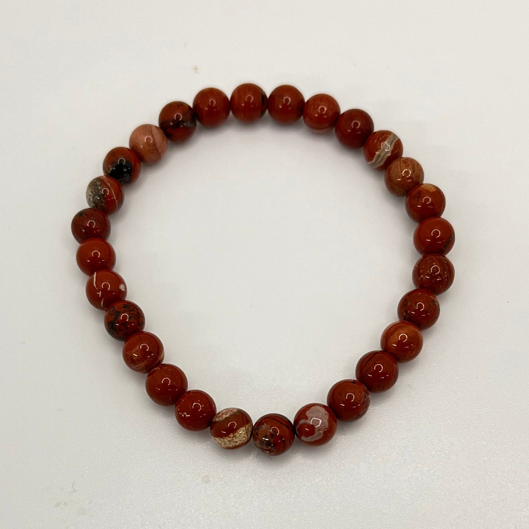 Rust colored beaded bracelet on a white background. Many of the beads have white, tan, brown, or black marbling. 