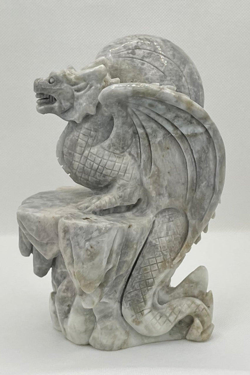 Stone sculpture of a dragon-like creature on a white background
