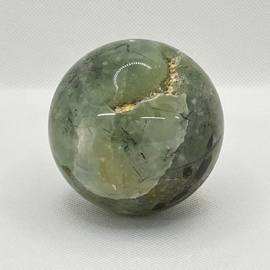 Green stone sphere on a white surface with a blurred background