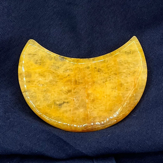Yellow crystal crescent moon on its side on a blue background.