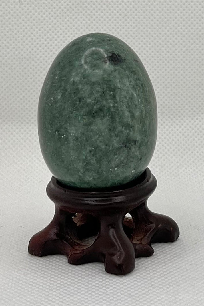 Green egg-shaped object on a stand against a plain background