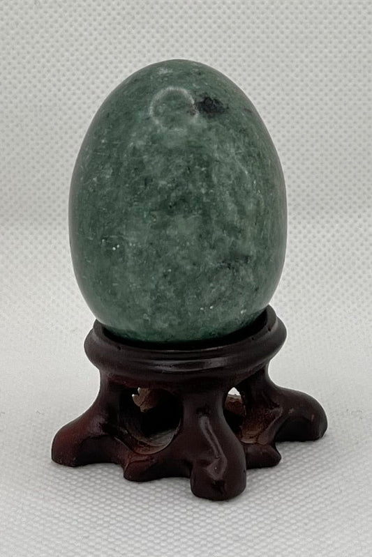 Green egg-shaped object on a stand against a plain background
