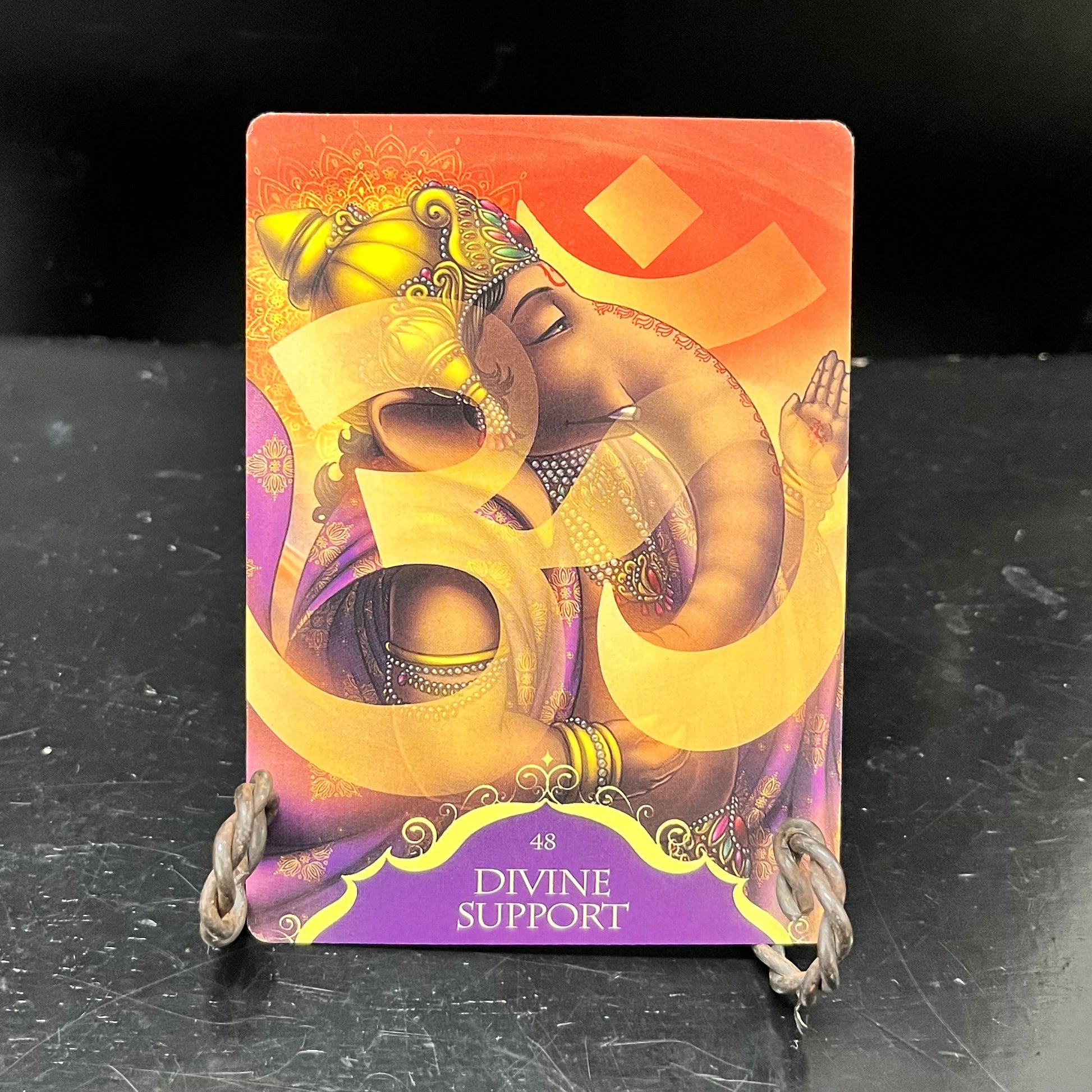 A card features an elephant in jewelry and an ornate headpiece with a sanskrit letter in yellow.  Text below appears on a purple background, saying "48 Divine Support"