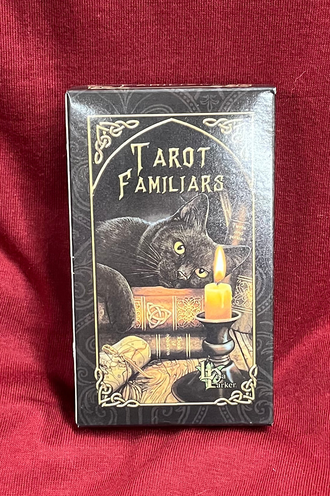 A vintage-style tarot deck box labeled 'Tarot Familiars' with an illustration of a black cat resting on a stack of old books. 