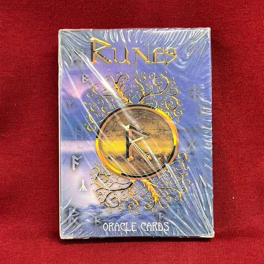 A boxed deck of 'Runes' Oracle Cards, still sealed in plastic wrap, displayed on a red fabric surface.