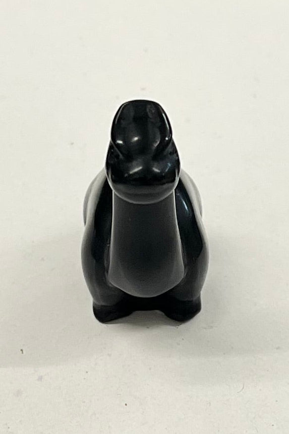 A small shiny obsidian dinosaur from the front view.