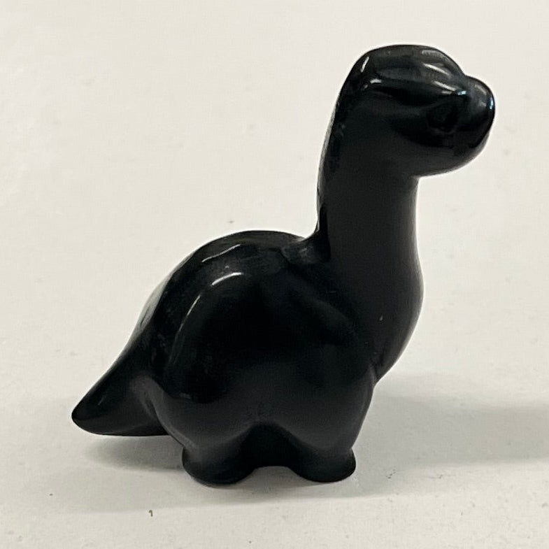 A small black polished stone dinosaur figurine displayed on a white rectangular board.
