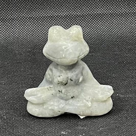 Figurine of a gray and black slightly irridescent frog with its eyes closed and its legs crossed, appearing to be meditating.