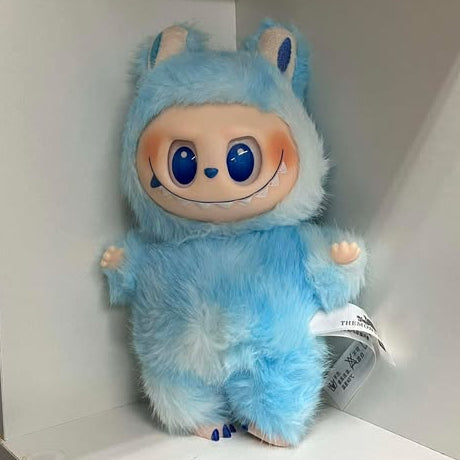 Plush toy with a fuzzy light blue design on a white shelf.  It has blue eyes, a blue nose, a wide smile showing many teeth, a spot of blush on each cheek, and plastic hands and feet.  The feet have three toes with painted nails. 