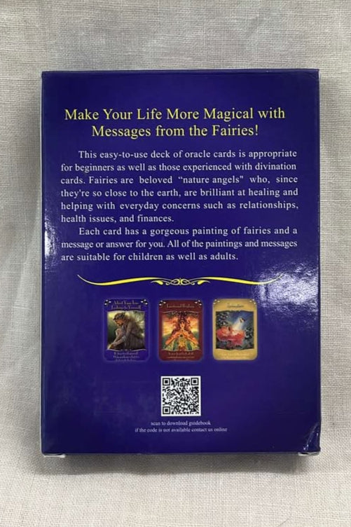 Tarot card deck back is blue with yellow writing and card images  on a textured surface.  Text at the top says "Make your life more magical with messages from the fairies." 