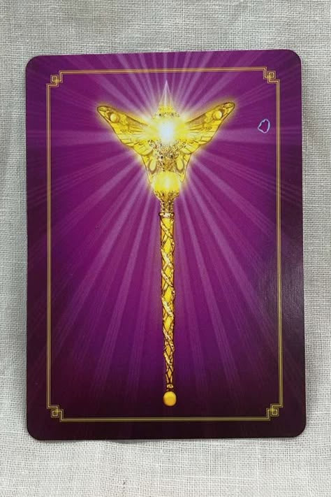 Purple card back with a gold butterfly-topped staff radiating light from a crystal in the center of the butterfly.  background