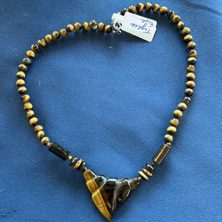 Tiger's eye beads and a triangular pendant on a blue fabric background