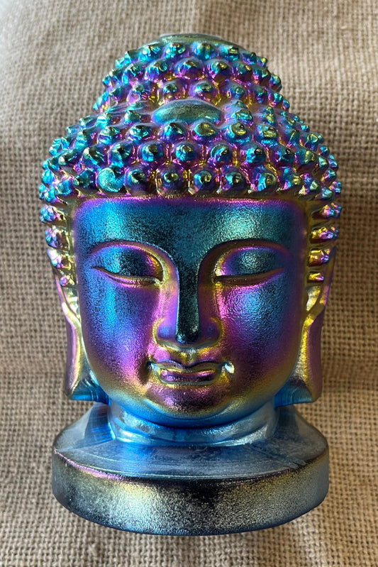 Colorful reflective Buddha head statue on a textured surface