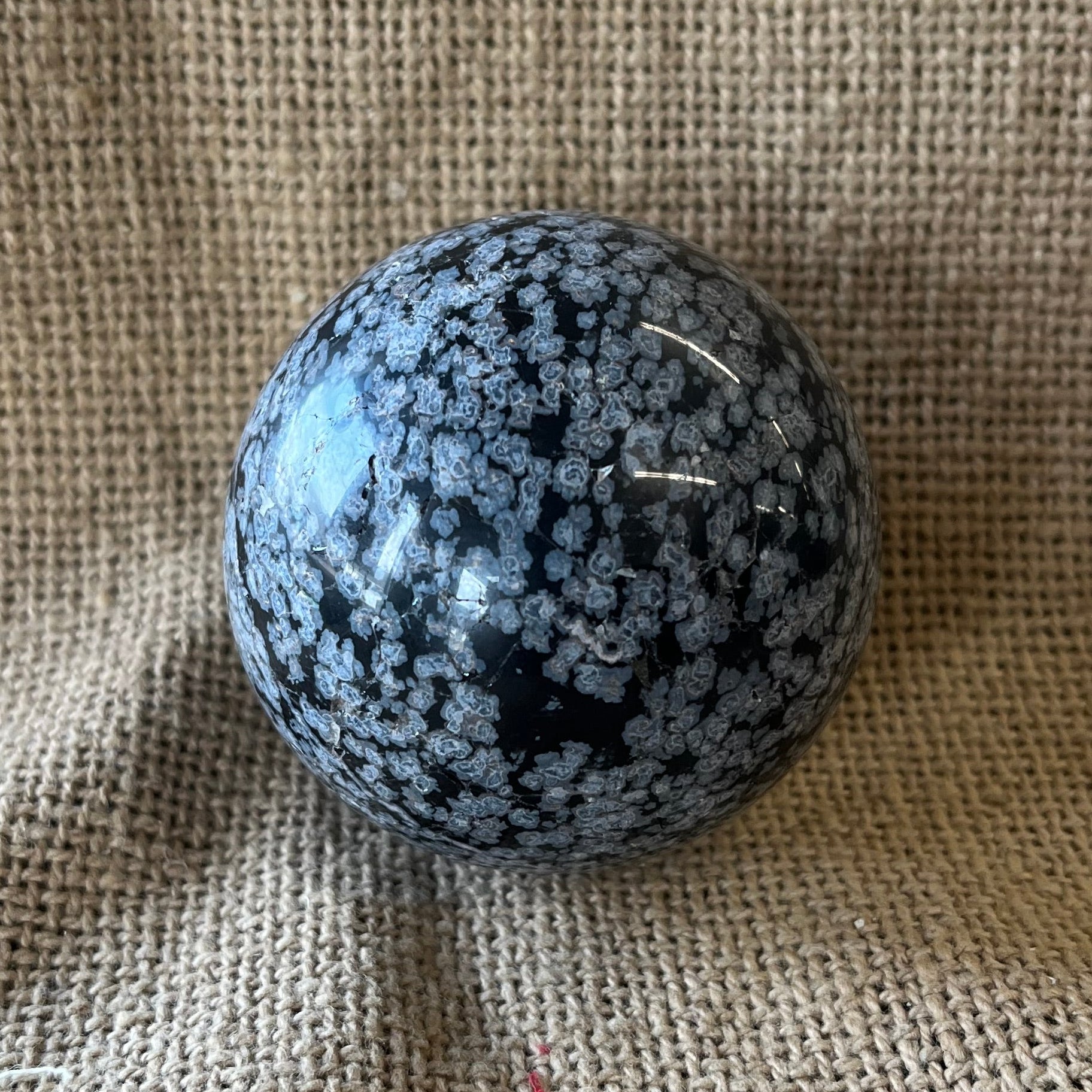 Black sphere with white snowflake pattern on a textured fabric background