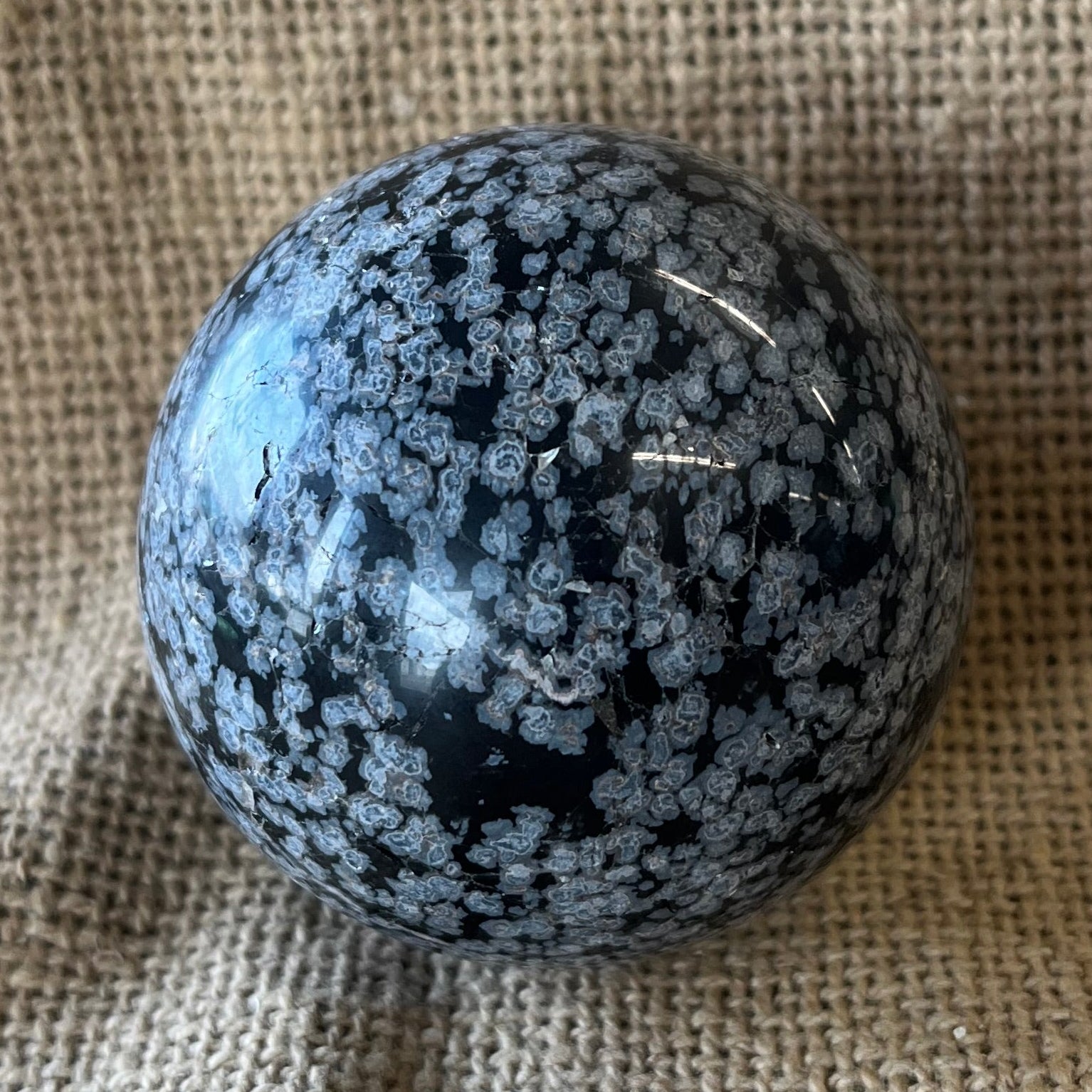 Black sphere with white snowflake pattern on a textured fabric background