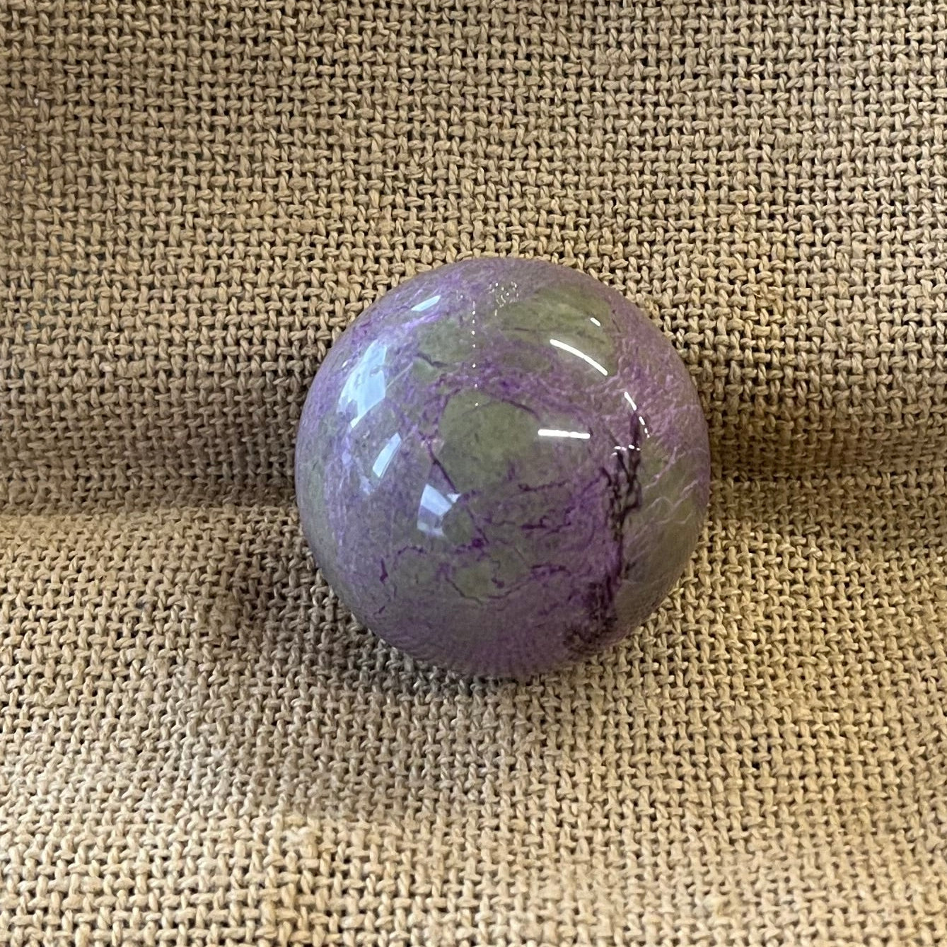 Purple marbled crystal ball on a textured beige surface