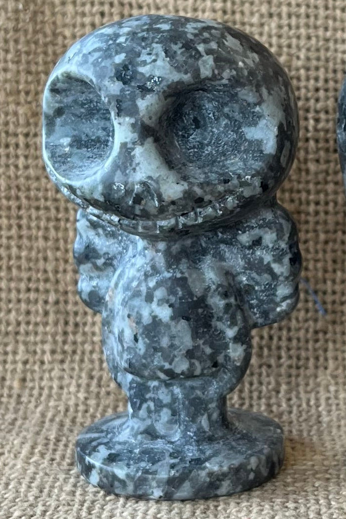 Gray and blac stone figurines of Jack and Sally on a tan textured background.